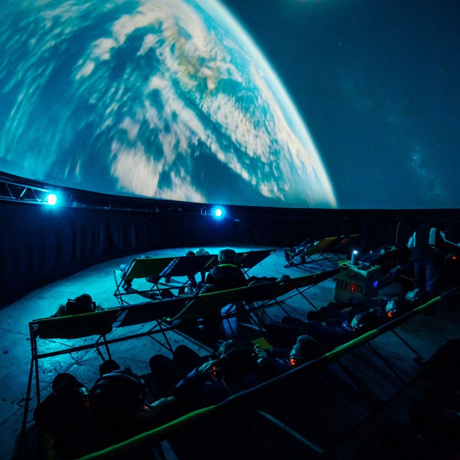 Audience watches an immersive Earth-from-space projection inside a planetarium.