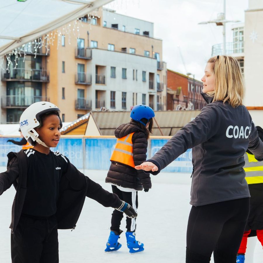 Ice skating coach guiding children during a school skating session at Ice Cube