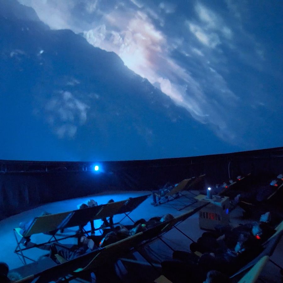 Visitors watch a 360° projection of Earth from space inside an immersive planetarium dome.