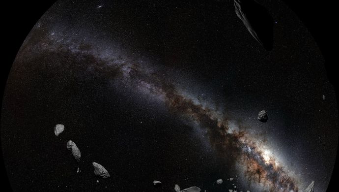 Asteroids floating against a backdrop of the Milky Way galaxy and a dense field of stars.
