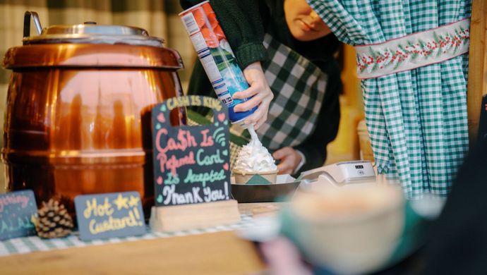 Whipped cream being added to a hot festive drink