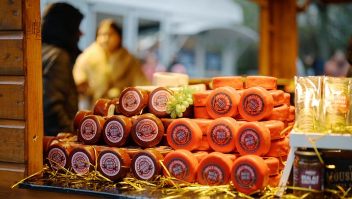 Display of cheese stacked on a market counter.