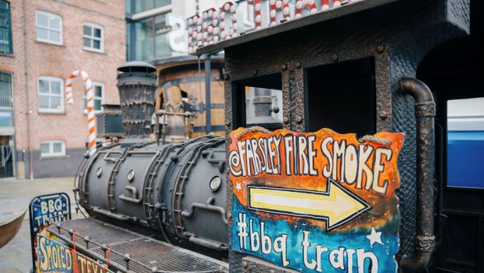 Old railway engine turned food stall decorated with colourful signage at the Christmas market.