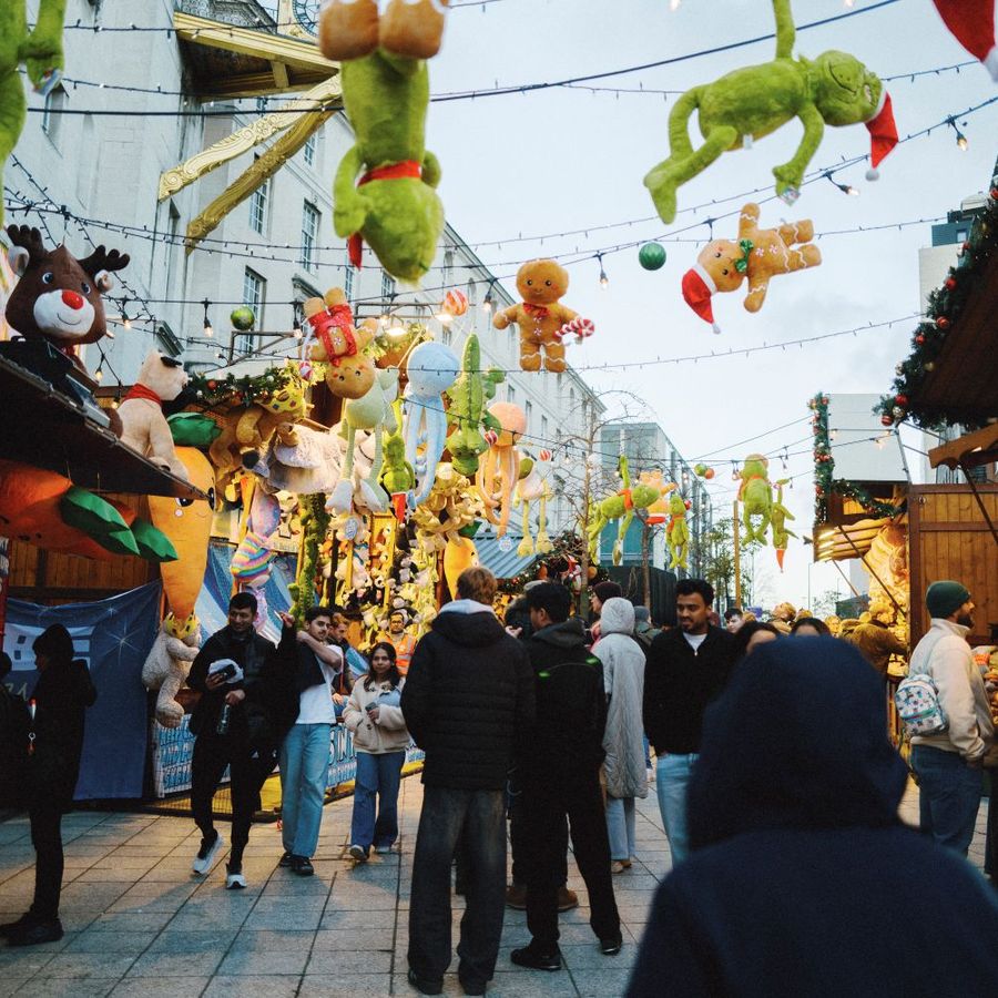 Visitors walking through festive market stalls with overhead decorations