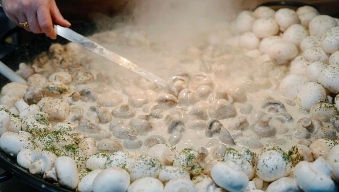 Garlic mushrooms cooking on a large hotplate.