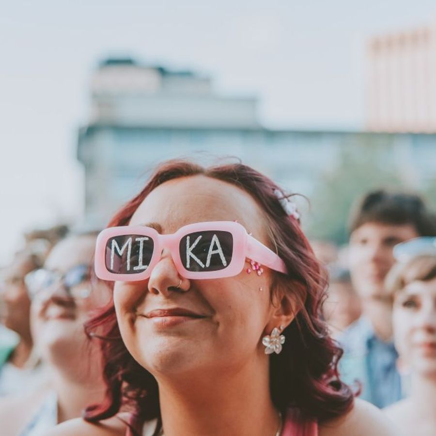 Concertgoer wearing pink “MIKA” sunglasses in a crowd at Millennium Square Leeds during Mika’s 2025 Summer Series performance