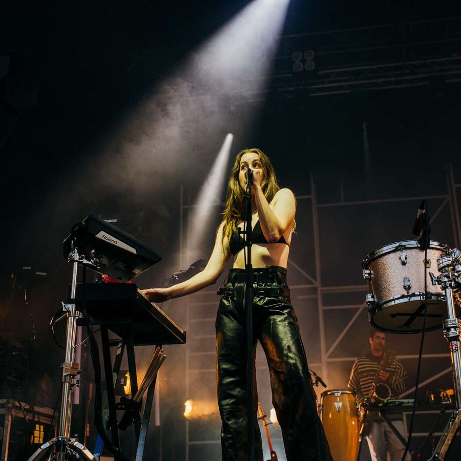 Performer at keyboard singing into microphone with spotlight beam from above.