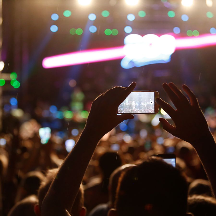 Person holding up a phone to take a picture of a performance on stage