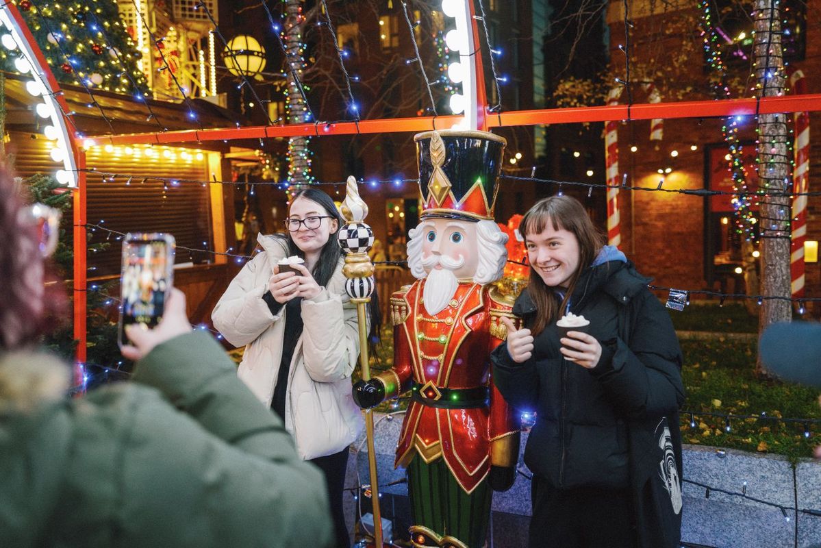 Visitors posing with a festive nutcracker statue