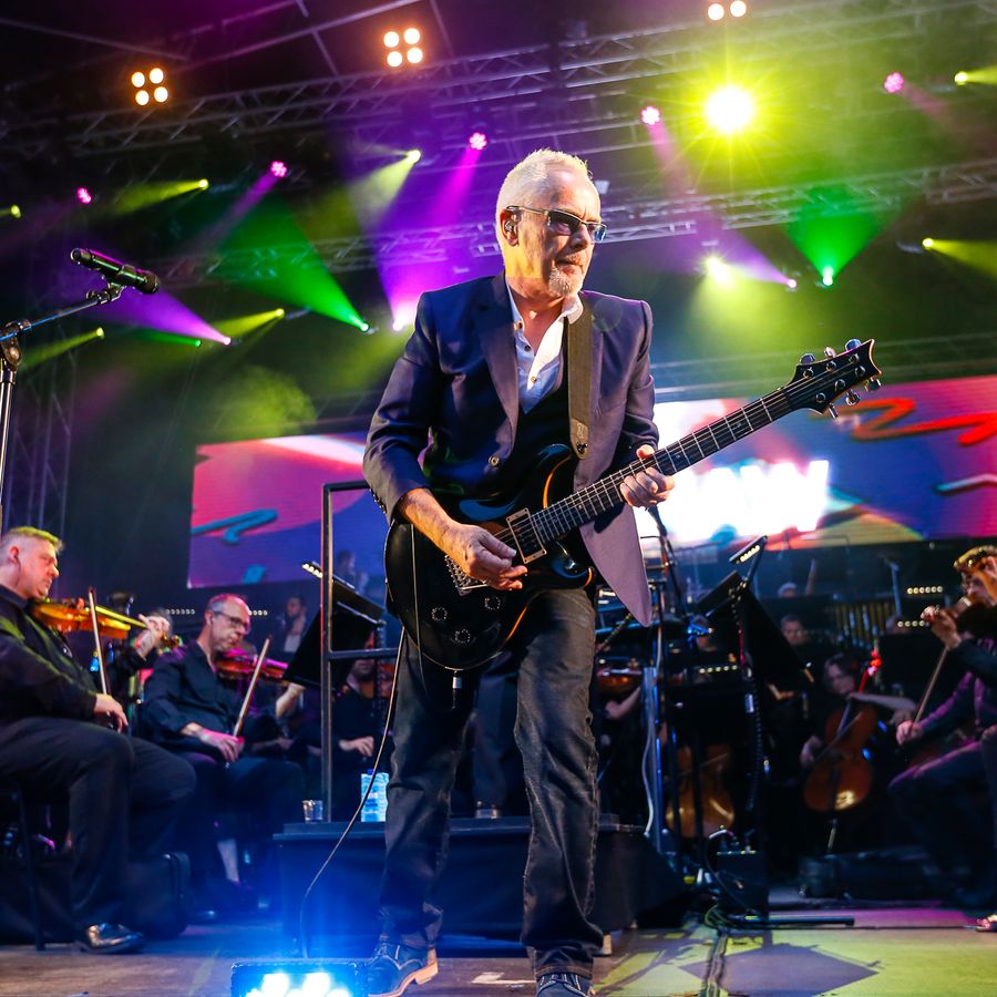 Nik Kershaw playing the guitar in front of the Orchestra of Opera North