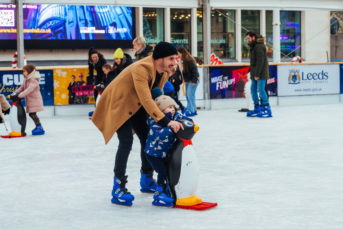 A man and a child ice skating on Millennium Square