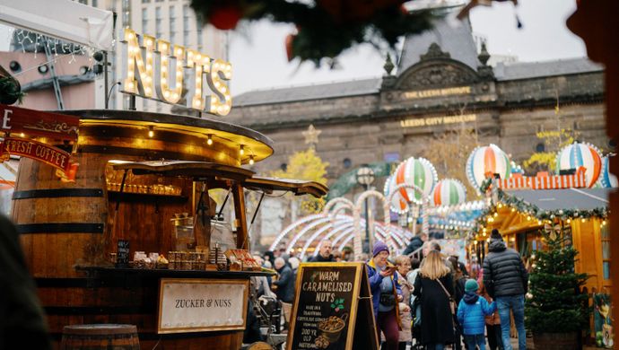 Festive market stall with illuminated decorations and visitors browsing.