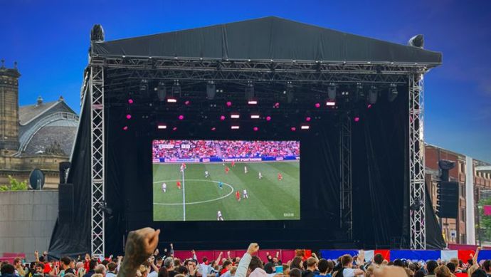 Football game broadcast on a stage screen