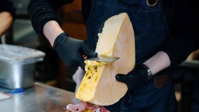 Fresh raclette cheese being melted over a loaded dish.