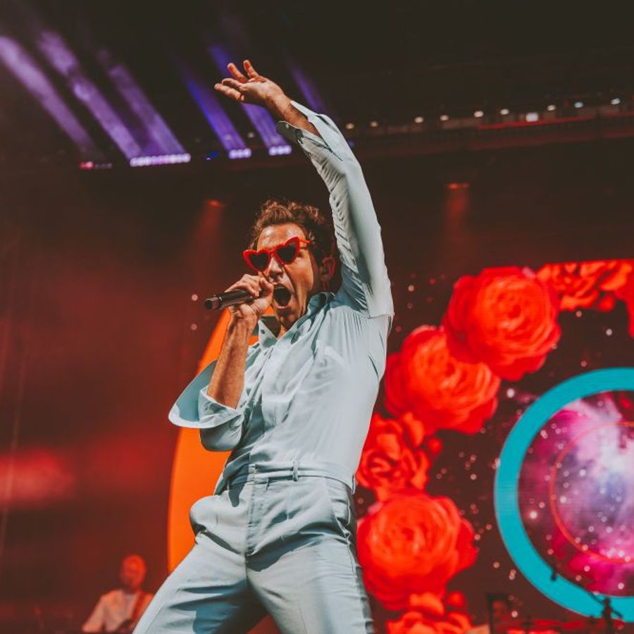 Mika singing on stage with colourful screen visuals at Millennium Square Leeds during the 2025 Summer Series